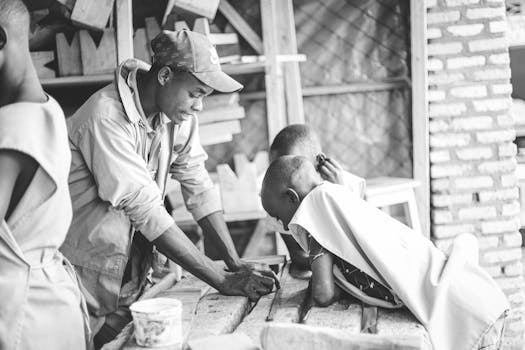 A mentor guides young boys in a carpentry workshop, fostering skill and curiosity in woodworking.