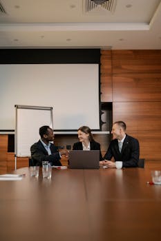 Three professionals engaging in a handshake during a business meeting in a modern office setting.