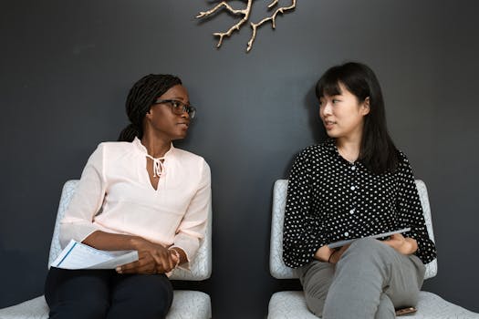 Two professional women engaging in a business discussion indoors.