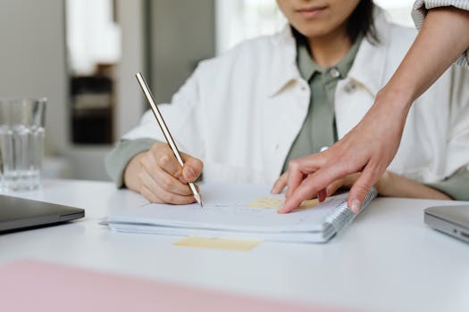 Two professionals collaborating and taking notes in a modern office setting.