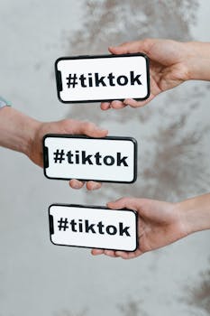 Hands holding smartphones displaying TikTok hashtag, emphasizing social media connection.