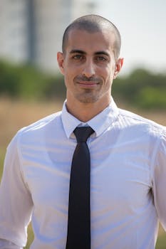 Portrait of a confident businessman in a white shirt and tie smiling outdoors.