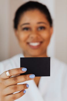 Smiling woman presenting a blank black card, ideal for business or branding concepts.