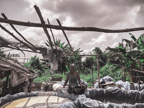 A woman in Nigeria works outdoors amidst lush greenery and cloudy skies.