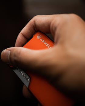 A close-up of a hand holding an orange wallet, showcasing style and functionality.