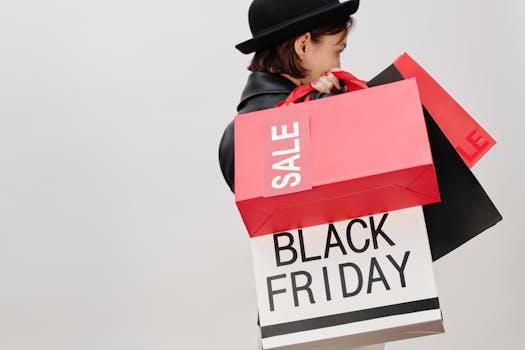 A stylish woman carrying Black Friday sale shopping bags against a neutral background.