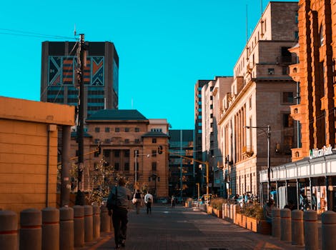 A vibrant city street scene with people walking among urban architecture and buildings.